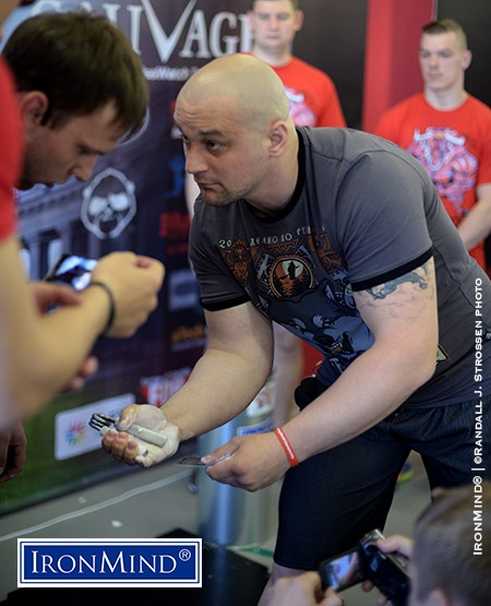 Surrounded by cameras, Nikolay Pleshakov (188 cm, 109 kg) awaited the signal from referee Dmitriy Suhovarov (left) and then pounded the Captains of Crush No. 3 gripper shut. IronMind® | ©Randall J. Strossen photo