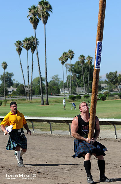 With Francis Brebner ready to score his effort, Dan McKim is about to launch the caber in Pleasanton last year, where he won both the 2010 Invitational U.S. Heavy Events Championships and the IHGF World Caber Championships.  IronMind® | Randall J. Strossen photo.  