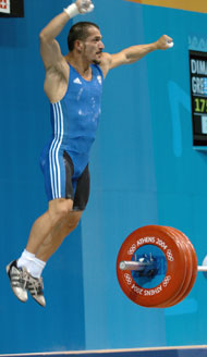 Pyrros Dimas (Greece) celebrates his successful 175-kg snatch at the 2004 Olympics, where he won the bronze medal - a very nice addition to the gold medals he had won in each of the previous three Olympics. IronMind® | Randall J. Strossen, Ph.D. photo.