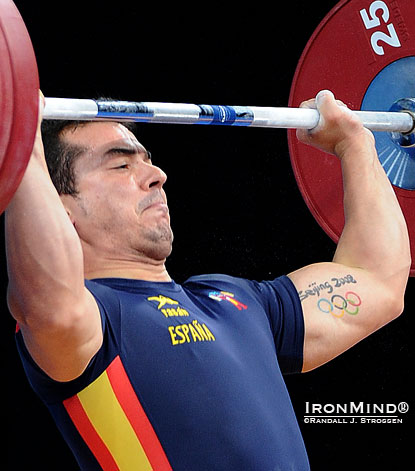 Jose Navarro (Spain) drives under a jerk at the recent Olympic Test Event in London—notice that his hands are out at the snatch ring on the bar.  Incidentally, wonder how Jose spent his summer of 2008?  His left arm tells the story.  IronMind® | Randall J. Strossen photo.