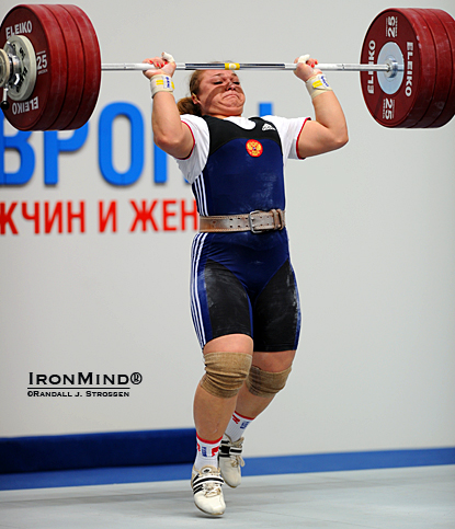 On her way to completing a 181-kg clean and jerk, Tatiana Kashirina drives her body under the bar, splitting her feet front and back.  Kashirina broke two world records in the womens' superheavyweight (+75 kg) category. IronMind® | Randall J. Strossen photo.