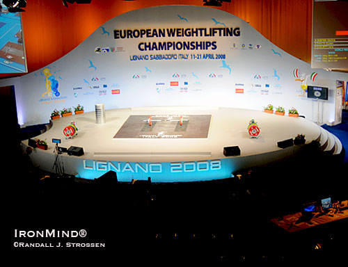 The 2008 European Weightlifting Championships (Lignano Sabbiadoro, Italy) were a sight to behold: nary a straight line to be found on stage, where curves danced instead, the stage was bright while the surrounding area was dark.  Drama had come to weightlifting and in the September 2008 issue of MILO, Randall Strossen wrote, “What the EWF accomplished can hardly be overstated,” in an article entitled “Best Staging, Best Lighting . . . The New Look of Weightlifting.”  IronMind® | Randall J. Strossen photo.