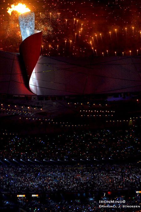 Where the world was last night: The Olympic cauldron was lit for a packed house of nearly 100,000 people, but that was only a fraction of the global audience watching spellbound as Chinese gymnast Li Ning danced along the upper rim of the stadium before lighting the Olympic cauldron. IronMind® | Randall J. Strossen, Ph.D. photo. Where the world was last night: The Olympic cauldron was lit for a packed house of nearly 100,000 people, but that was only a fraction of the global audience watching spellbound as Chinese gymnast Li Ning danced along the upper rim of the stadium before lighting the Olympic cauldron. IronMind® | Randall J. Strossen, Ph.D. photo.