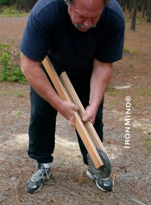 John Brookfield demonstrates the stick lift exercise using a barbell plate; notice how he has choked-up on the sticks to lessen the difficulty of the exercise why levering the sticks up and down.  IronMind® | Photo courtesy of John Brookfield. 