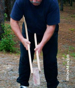 Here John uses a brick instead of a weight plate.  Notice the increased difficulty of the exercise by the placement of the sticks on the brick:  the brick will want to wobble and slip free of the sticks; therefore, you will need to exert more pressure to keep it in place.  IronMind® | Photo courtesy of John Brookfield. 